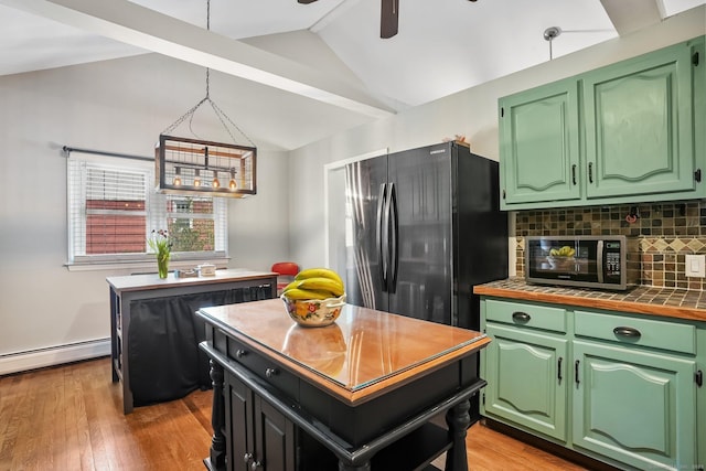 kitchen featuring tasteful backsplash, baseboard heating, freestanding refrigerator, stainless steel microwave, and lofted ceiling
