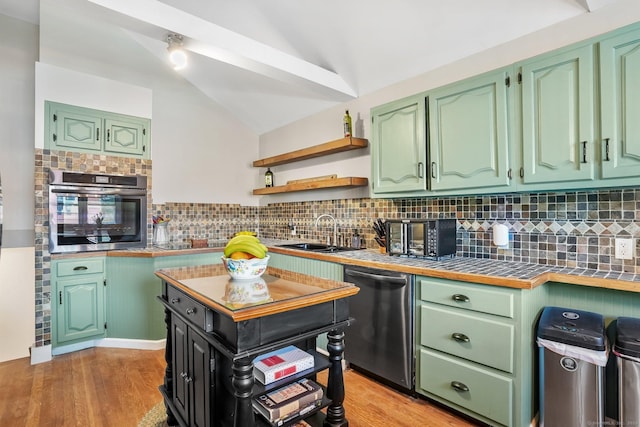 kitchen featuring lofted ceiling, tile counters, a sink, light wood finished floors, and stainless steel appliances