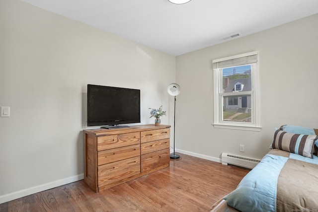 bedroom with light wood-style floors, baseboards, a baseboard radiator, and visible vents