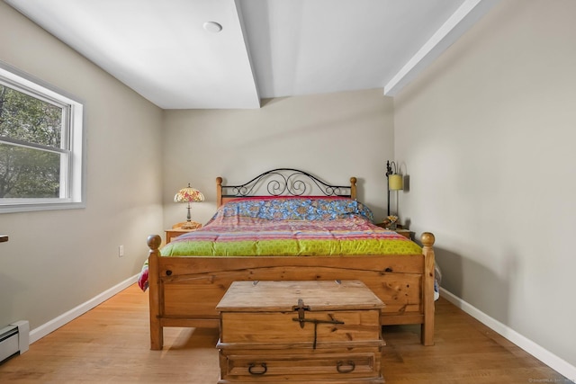bedroom with light wood-style floors, baseboards, and a baseboard heating unit