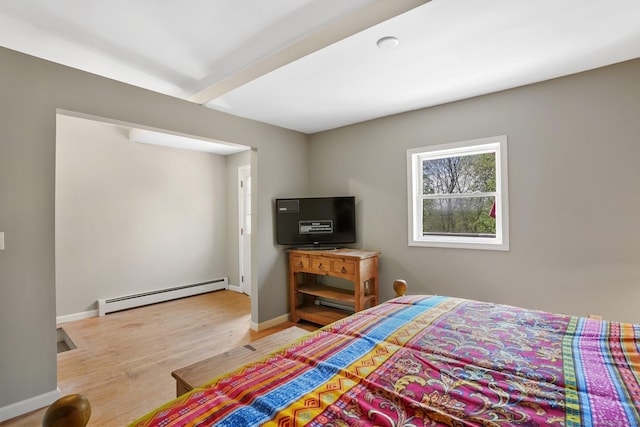 bedroom featuring baseboards, a baseboard heating unit, and wood finished floors