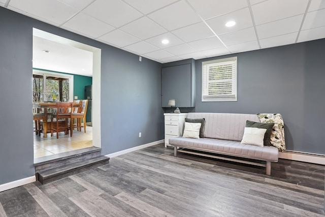 sitting room featuring a paneled ceiling, baseboards, a wealth of natural light, and wood finished floors