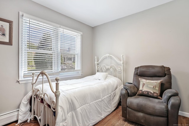 bedroom with baseboards, a baseboard radiator, and wood finished floors