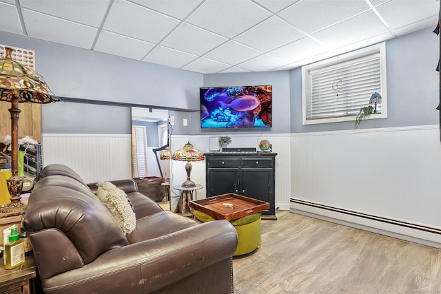 living area with a wainscoted wall, wood finished floors, and a paneled ceiling