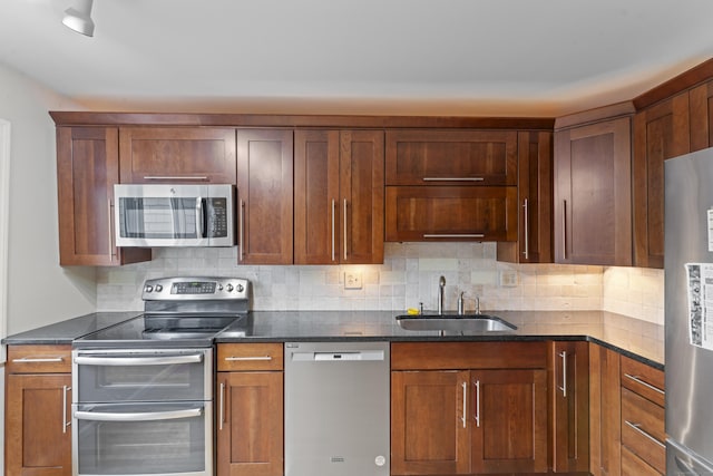 12 Boulevard Dr Unit 21-130, Danbury, CT 06810 - kitchen with appliances with stainless steel finishes, a sink, decorative backsplash, dark stone countertops, and brown cabinetry