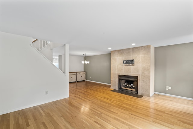 12 Boulevard Dr Unit 21-130, Danbury, CT 06810 - unfurnished living room featuring stairs, baseboards, light wood-style floors, a tiled fireplace, and a chandelier
