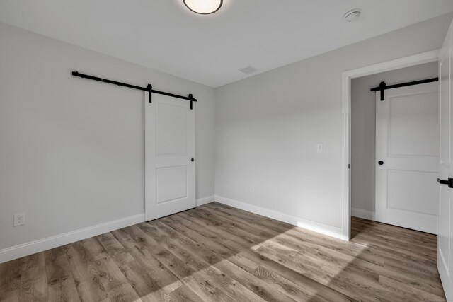 29 Sterling St, New Britain, CT 06053 - unfurnished bedroom with a barn door, wood finished floors, and baseboards