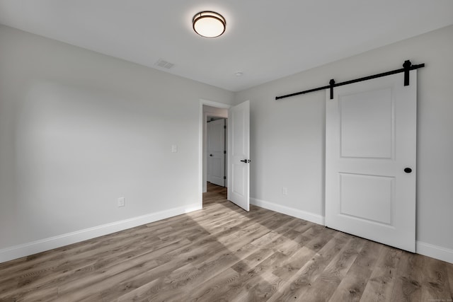 29 Sterling St, New Britain, CT 06053 - unfurnished bedroom featuring a barn door, baseboards, and wood finished floors
