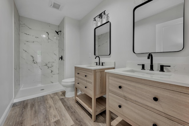 29 Sterling St, New Britain, CT 06053 - bathroom featuring a marble finish shower, two vanities, toilet, and wood finished floors