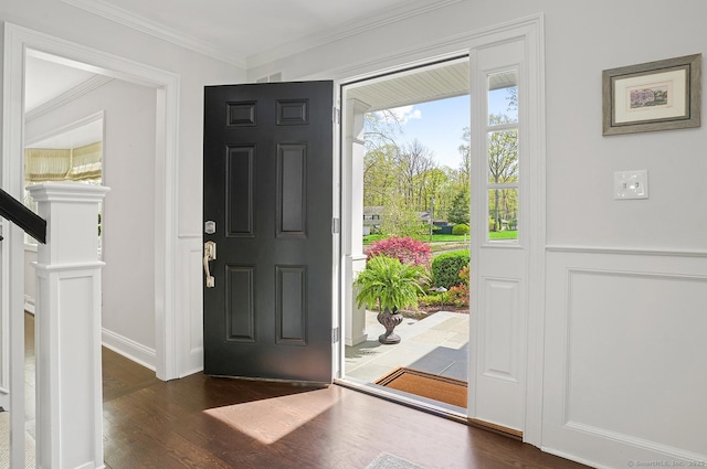 foyer featuring ornamental molding, a wainscoted wall, stairway, and dark wood-type flooring
