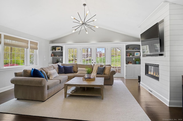 living area featuring a chandelier, dark wood finished floors, a large fireplace, built in features, and vaulted ceiling