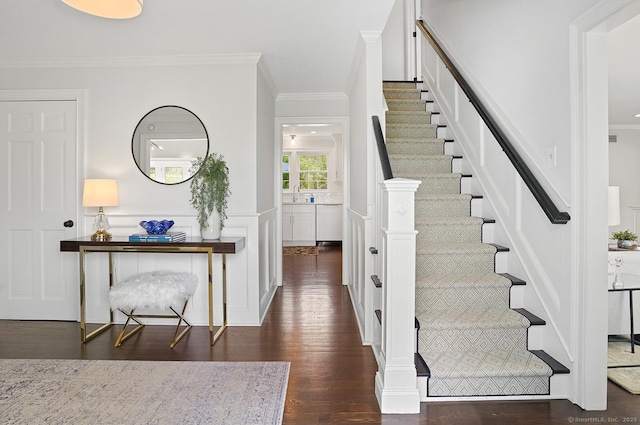 entryway featuring crown molding, stairs, wood finished floors, and a wainscoted wall