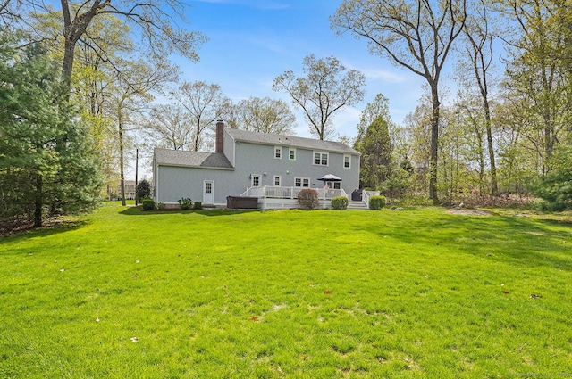 back of property with a lawn, a chimney, and a deck