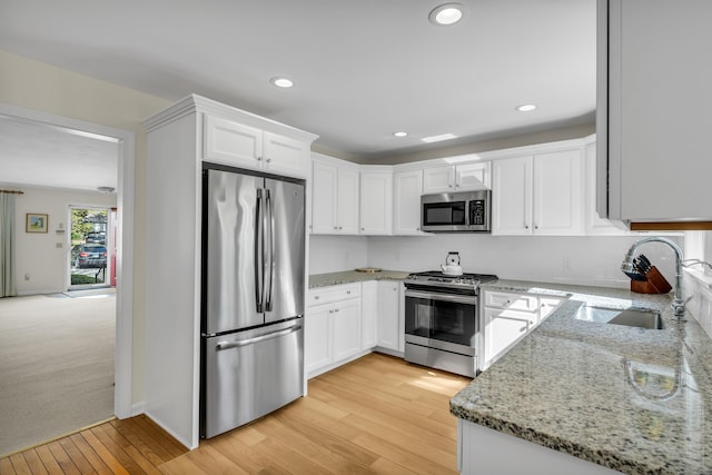 kitchen with white cabinetry, appliances with stainless steel finishes, a sink, and light wood-style flooring