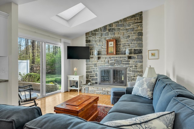 living room with a fireplace, lofted ceiling with skylight, and wood finished floors
