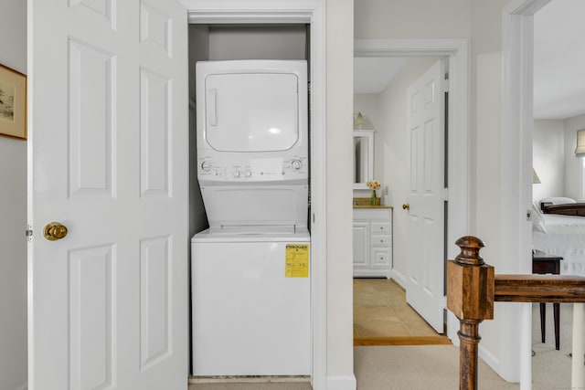 laundry room featuring stacked washer and dryer, laundry area, and light tile patterned floors