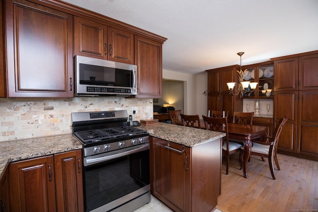 17 Ives Hill Ct Unit 17, Cheshire, CT 06410 - kitchen featuring appliances with stainless steel finishes, a peninsula, backsplash, hanging light fixtures, and a chandelier