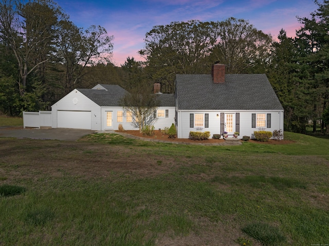 view of front of home featuring an attached garage, a shingled roof, a front lawn, and a chimney