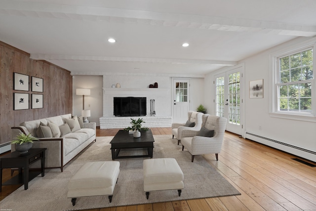 living room with beam ceiling, a fireplace, wood walls, hardwood / wood-style floors, and a baseboard heating unit