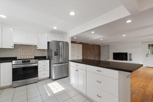 kitchen featuring dark countertops, white cabinets, stainless steel appliances, and open floor plan