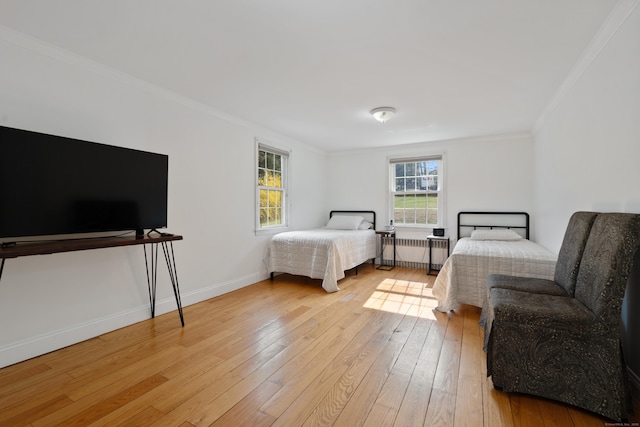bedroom with light wood-type flooring, radiator, crown molding, and baseboards
