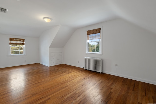 bonus room featuring visible vents, radiator heating unit, a healthy amount of sunlight, and wood finished floors