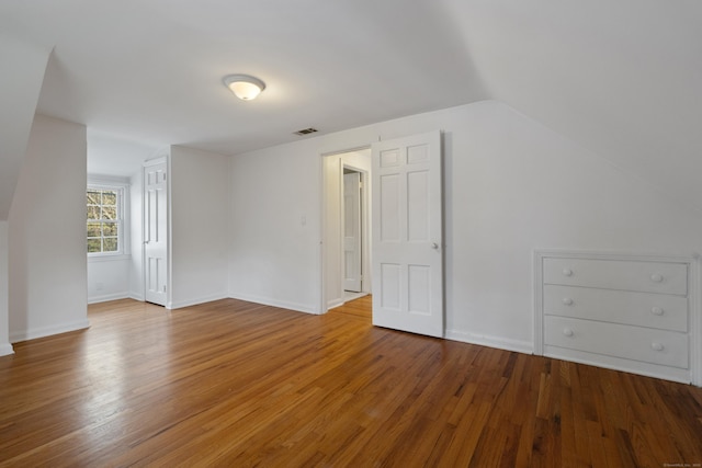 bonus room featuring baseboards, vaulted ceiling, wood finished floors, and visible vents