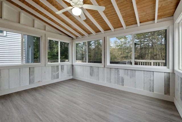 unfurnished sunroom with wood ceiling, wood finished floors, baseboards, lofted ceiling with beams, and wooden walls
