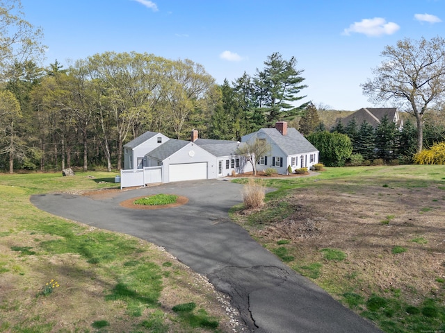 view of side of property with a lawn, driveway, a chimney, and a garage