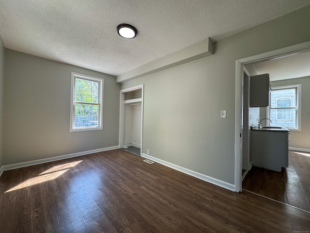 unfurnished bedroom with baseboards, a textured ceiling, and dark wood-type flooring