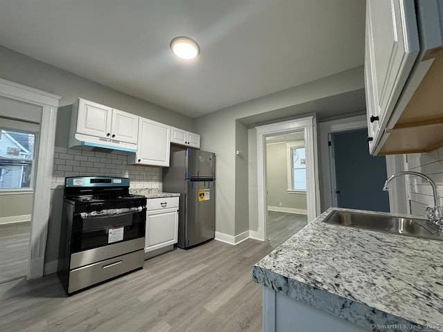 kitchen featuring a sink, stainless steel range, freestanding refrigerator, white cabinets, and under cabinet range hood
