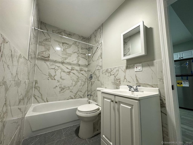 bathroom featuring vanity, toilet, tile walls, and bathtub / shower combination