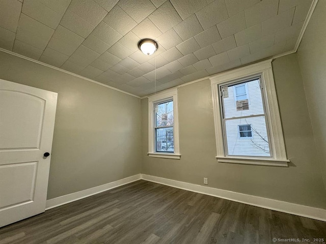 unfurnished room featuring baseboards, ornamental molding, and dark wood-type flooring