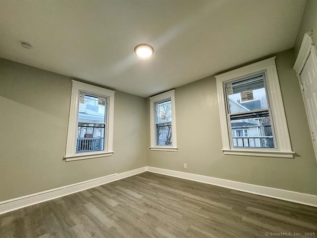 spare room featuring baseboards and dark wood-style flooring