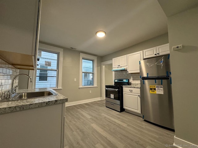 kitchen featuring a sink, light wood finished floors, stainless steel appliances, tasteful backsplash, and under cabinet range hood