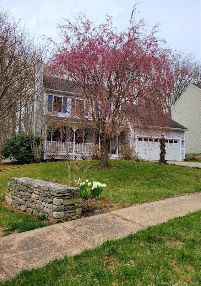 view of front of house with driveway, a porch, and a front lawn
