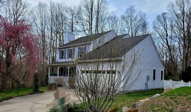 view of property exterior featuring fence, covered porch, and a chimney