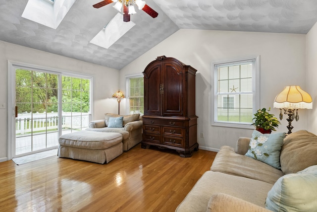 interior space with a healthy amount of sunlight, ceiling fan, light wood-type flooring, and vaulted ceiling with skylight
