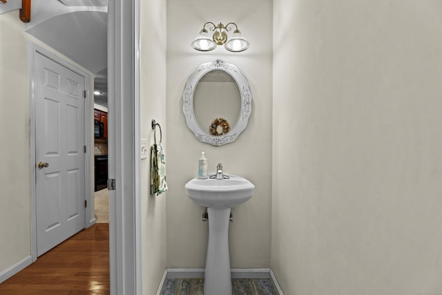 bathroom featuring baseboards, wood finished floors, and a sink