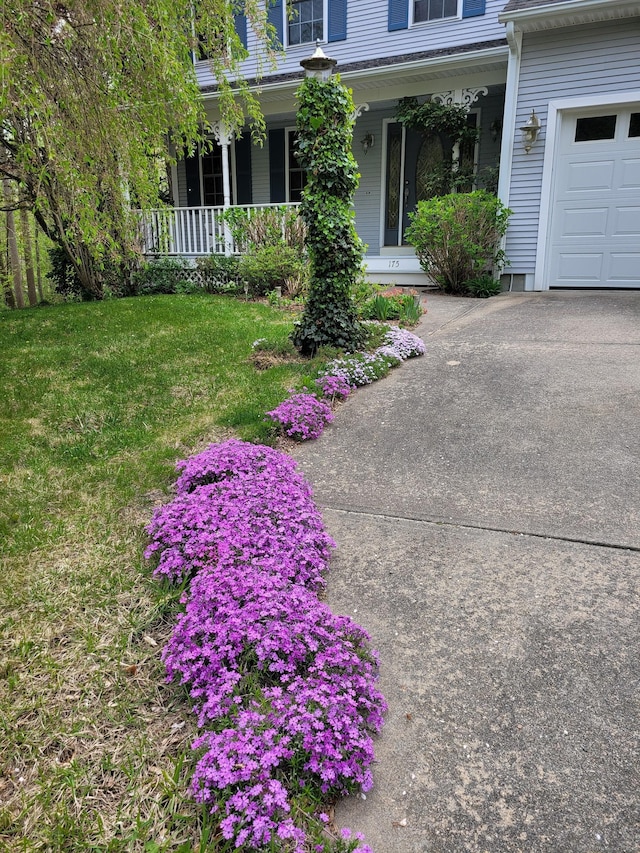 view of grassy yard with a porch and driveway