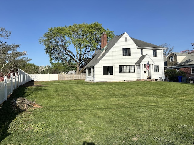 exterior space featuring a fenced backyard, a chimney, a yard, and roof with shingles