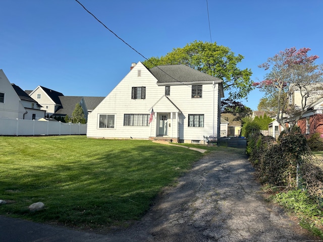 colonial inspired home with a front lawn, fence, and a chimney