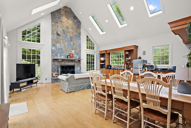 132 Belden Hill Rd, Wilton, CT 06897 - dining area featuring a skylight, high vaulted ceiling, light wood-style floors, a stone fireplace, and recessed lighting