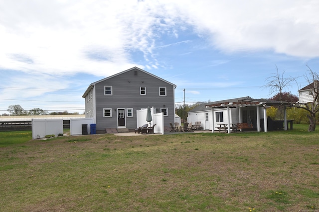 rear view of property featuring fence, a patio, and a yard