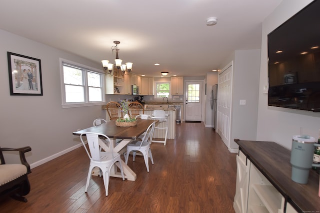 dining area with plenty of natural light, dark wood-style flooring, and a notable chandelier