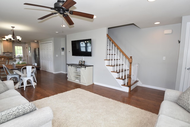 living area featuring baseboards, ceiling fan with notable chandelier, stairs, and wood finished floors