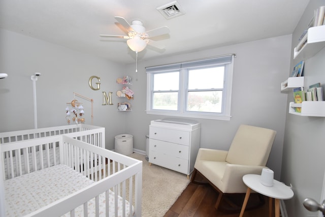 bedroom with a nursery area, ceiling fan, and visible vents