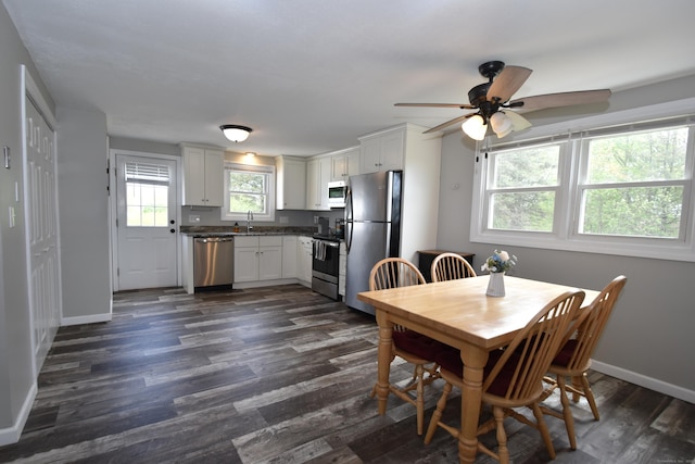 dining space with baseboards, a ceiling fan, and dark wood-type flooring