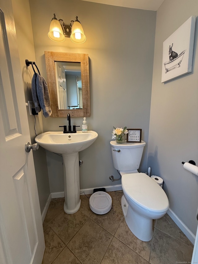 bathroom with toilet, tile patterned floors, a sink, and baseboards