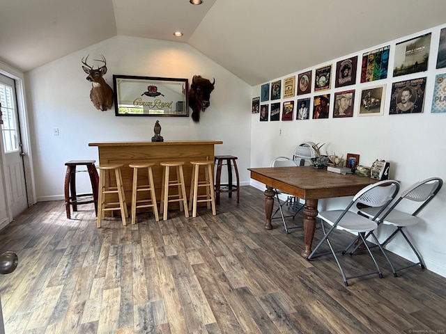 dining room featuring lofted ceiling, wood finished floors, baseboards, recessed lighting, and a bar